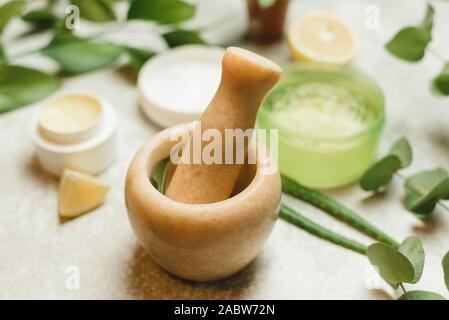 mixing ingredients to create cosmetics in a marble mortar. Herbal cosmetic ingredients. A mixture of aloe leaves, eucalyptus branches, lemon to create a gel, skin cream. Stock Photo