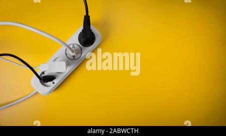 electricity consumption - electric extension cord full of power plugs on yellow background with copy space. top view Stock Photo