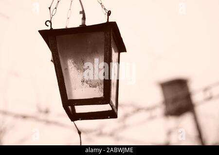 Old retro lantern hanging on a chain in the garden. Sepia photo. Stock Photo