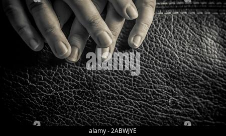 A close up of a woman's fingers on a leather chair in black and white Stock Photo