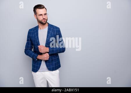 Photo of serious pensive pondering man fastening buttons on sleeves looking pensively into empty space in white pants spectacles isolated grey color Stock Photo