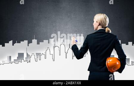 Businesswoman draws silhouette of business center Stock Photo