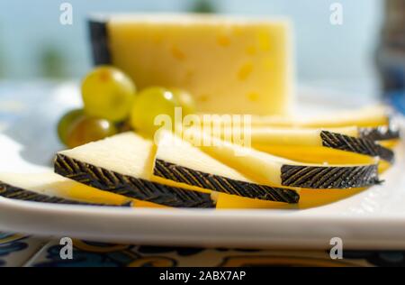 Spanish sheep cheese served with white grapes on andalusian style table outside with sea view Stock Photo