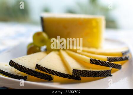 Spanish sheep cheese served with white grapes on andalusian style table outside with sea view Stock Photo