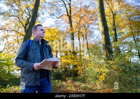 Active Mature Man With Map Walking Through Autumn Woodland In Slow Motion Stock Photo