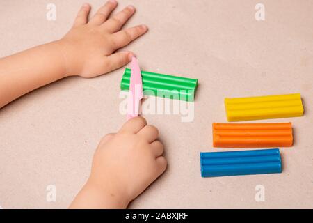 Kids hands colorful plasticine and toy knife Stock Photo