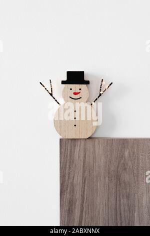 a funny wooden snowman, with a red nose and wearing a hat, against an off-white background with some blank space on top Stock Photo