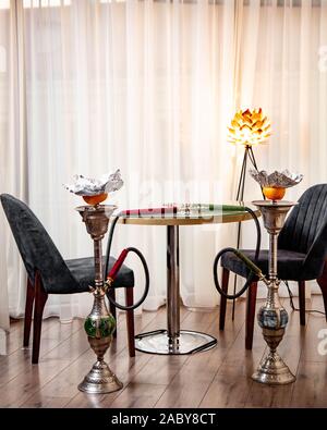 two hookah stands next to small round table and two chairs Stock Photo