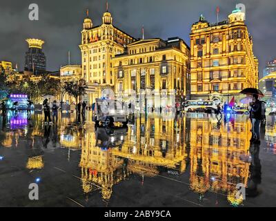 Night view of a reflection of the illuminated century-old western-style buildings on the wet ground in the rain at the promenade along the Bund in Sha Stock Photo