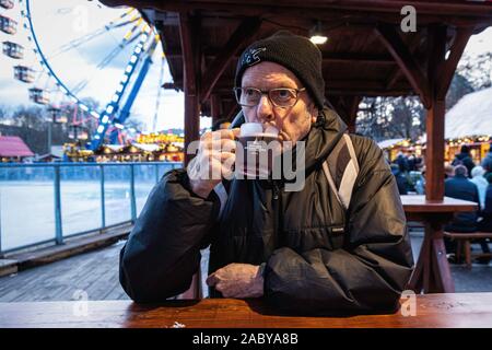 Elderly senior man drinking gluhwein at the Berliner Weihnachtzeit Christmas market, Alexanderplatz, Mitte, Berlin The Berliner Weihnachtzeit Stock Photo