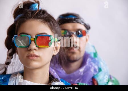 Woman and man wearing plastic on white background. Models in clothes and shoes made of garbage. Fashion, style, recycling, eco and environmental conce Stock Photo