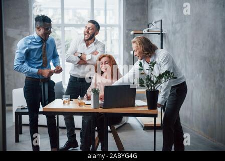New crazy idea. Young business team working on a project with laptop on table and smiling Stock Photo
