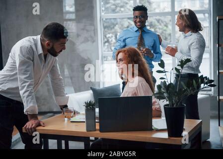 Friendly support. Young business team working on a project with laptop on table and smiling Stock Photo