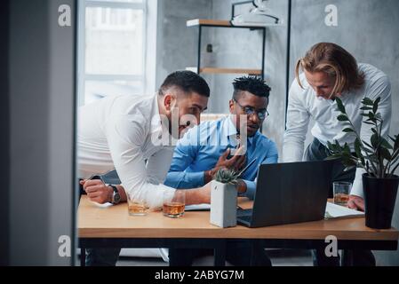 Serious man fully concentrated. Multiracial business people with laptop solving the company issues Stock Photo