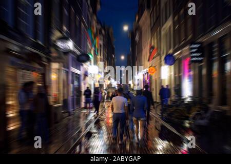 Blurry motion image of people walking on Warmoesstraat street in Amsterdam. It is one of the main shopping streets with cafes, restaurants and shops. Stock Photo