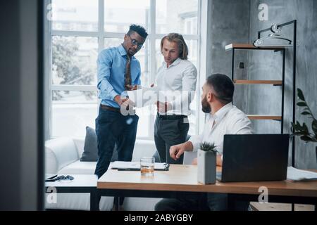 Reading a document. Three suit weared workers spending time making reports Stock Photo