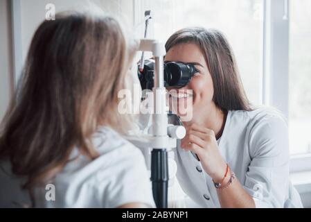 Working with passion. Process of diagnosing eye dysfunctions by female oculist with special equipment Stock Photo