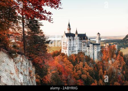 Autumn trees on the hill reveal a view on charming Neuschwanstein Castle Stock Photo