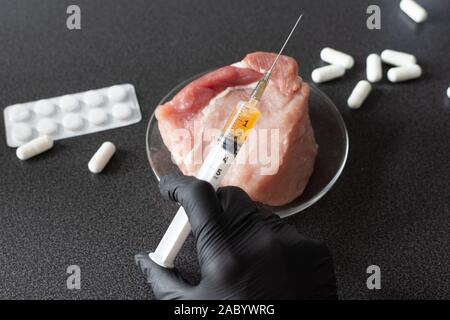 Researcher injecting GMO a slice of pork meat. Genetically modified organism, harmful for peples health. Meat with antibiotics concept. Stock Photo