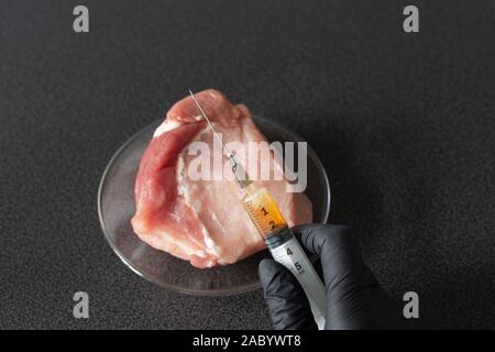 Researcher injecting GMO a slice of pork meat. Genetically modified organism, harmful for peples health. Meat with antibiotics concept. Stock Photo