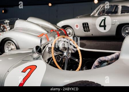 Side, close up view of grey retro sport coupe cabriolet interior: wooden steering wheel, dashboard, mirror, red number 2 painted on left door, multi Stock Photo