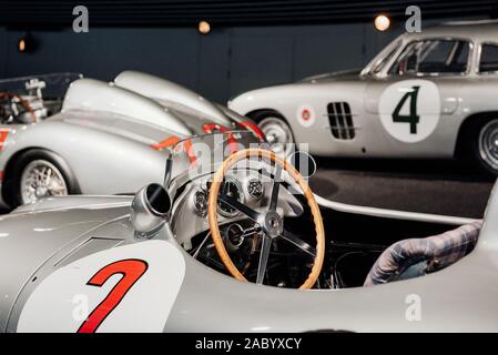 Side, close up view of grey retro sport coupe cabriolet interior: wooden steering wheel, dashboard, mirror, red number 2 painted on left door, multi Stock Photo