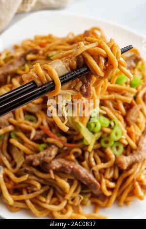 Eating Chinese beef lo mein noodles with chopsticks Stock Photo