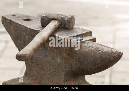 Old rusty hammer lies on the anvil. Blacksmith, metalsmith, farrier tools. Close view. Stock Photo