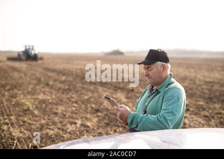 Modern senior farmer using tablet on the field Stock Photo