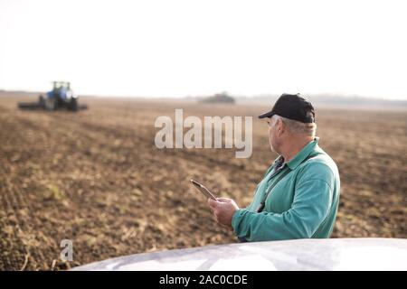 Modern senior farmer using tablet on the field Stock Photo