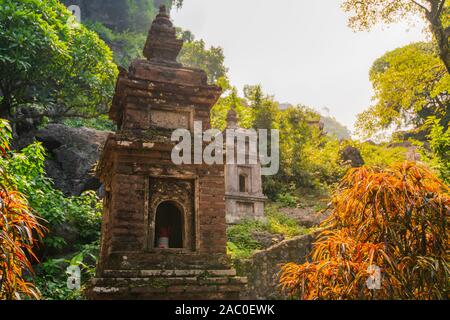 A small brick Pagoda at Bich Ding in Tam Coc, Vietnam with the sun shining behind it during a beautiful sunrise Stock Photo