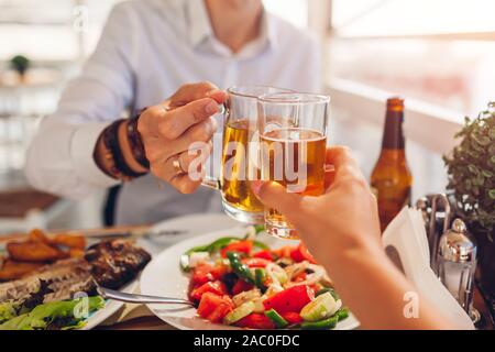 Romantic honeymoon dinner for two. Couple toasts and drinks alcohol. People eat greek salad and seafood in cafe Stock Photo