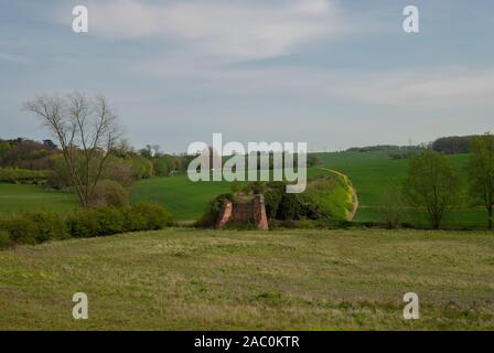 Remains of an old railway bridge from the Marlesford to Framlingham Line in Suffolk with a meadow in the foreground and farmed crop in the background Stock Photo