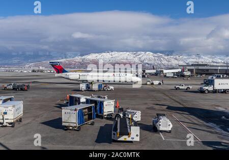 Delta aircraft taxiing at Salt Lake City airport Utah USA, with ground handlers on apron with white snow capped mountains in the background Stock Photo