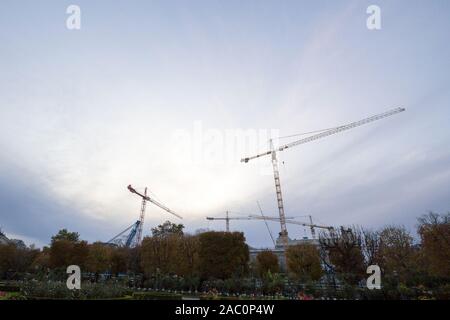 Group of cranes on a construction site in the city center of Vienna, Austria, in front of a building being assembled taken from afar during a cloudy e Stock Photo