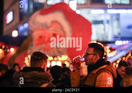 Berlin, Germany. 29th Nov, 2019. A visitor drinks mulled wine at the Christmas market on Alexanderplatz in Berlin, Germany, on Nov. 29, 2019. Credit: Shan Yuqi/Xinhua/Alamy Live News Stock Photo