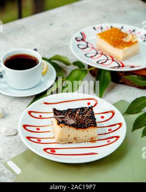 cheesecake piece garnished with chocolate syrup served with tea Stock Photo