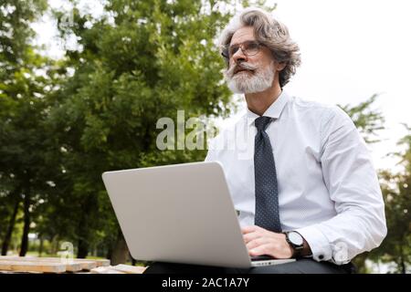 Thoughtful businessman using laptop computer outdoors Stock Photo