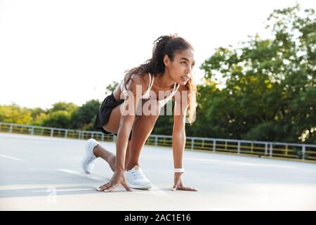 Photo of african american attractive woman in sportswear doing exercise while working out at playground outdoors Stock Photo