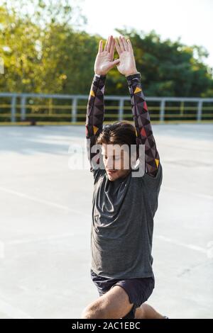 Photo of unshaven concentrated man in sportswear doing exercises while working out at playground outdoors Stock Photo