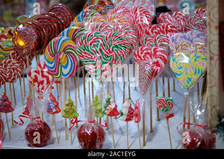 Display of colourful Christmas lollipops, many heart shaped on a market stand for sale, with sun flare on one of the candy Stock Photo