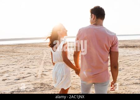 Back view of a beautiful young couple wearing summer clothing standing at the beach Stock Photo
