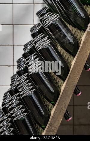 Sparkling wine bottles stacked up in old wine cellar close-up background Stock Photo