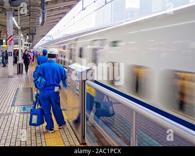 Shinkansen (Bullet Train) arriving at Tokyo Station, with cleaners waiting to clean the train. Stock Photo
