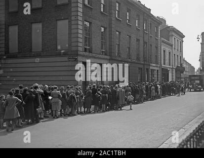 A long ration queue for bread in post World War II Britain c. 1946. This queue stretches along Anderson Street for T. Pritchard's bakery at 108 Kings Road, Chelsea, London, England, UK. To deal with food shortages during the war, the Ministry of Food began a system of rationing. People had to register at chosen shops, and had a ration book containing coupons. Rationed items included meat, dairy produce, tea and sugar. Rationing continued after the war – and bread was not rationed until after the war ended. A 'national loaf' of wholemeal bread replaced the ordinary white variety. Stock Photo