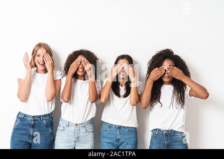 Photo of a pretty cheery smiling young women multiracial friends posing isolated over white wall background covering eyes. Stock Photo