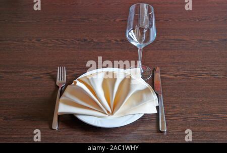 Towel on white plate, fork and knife on wooden table Stock Photo