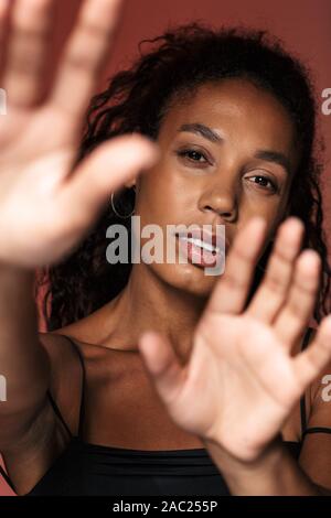 Image of pretty african young woman isolated over red wall background covering camera with hands. Stock Photo