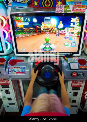 Tokyo, Japan - 12 Oct 2018: A boy is playing a Mario Cart video game at an amusement arcade in Tokyo, Japan. Stock Photo