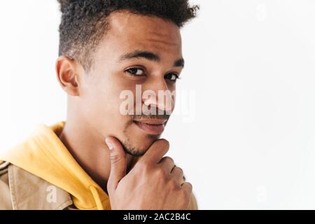 Image closeup of brooding african american guy wearing coat thinking and touching his chin in white studio Stock Photo